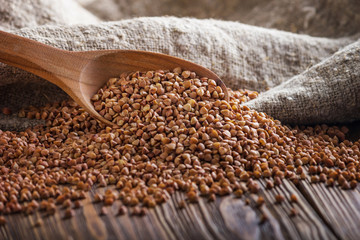Rural still-life - the peeled groats of buckwheat (Fagopyrum esculentum) on the background of burlap, closeup with selective focus