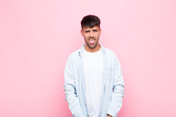 young handsome man feeling disgusted and irritated, sticking tongue out, disliking something nasty...