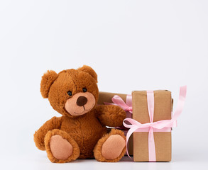 brown teddy bear, stack of gifts in boxes wrapped in brown paper