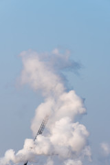 A single crane shrouded in smoke on a sunny day