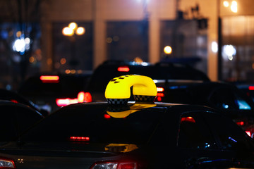 Taxi car with yellow checkered sign on city street in evening