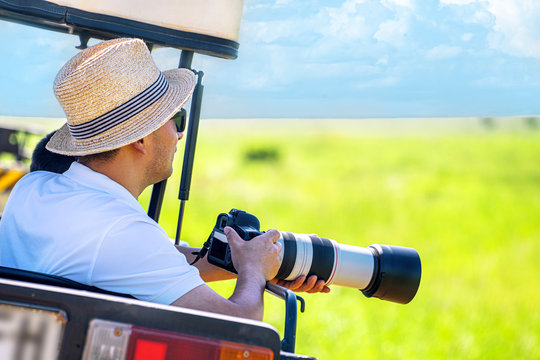 The man photographer takes a picture from touristic vehicle on tropical safari.