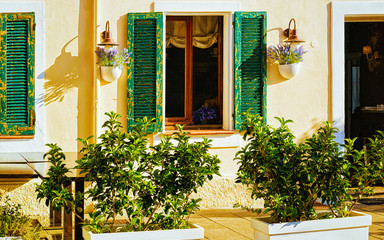 Fototapeta na wymiar Cozy house with flower pots at Corso Umberto I Street in Old city of Olbia on Sardinia Island in Italy. Town architecture on Italian Sardegna. Mixed media.
