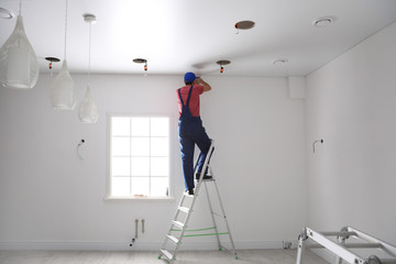 Worker installing stretch ceiling in empty room