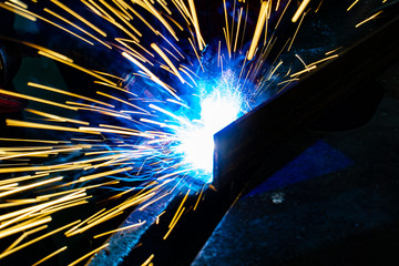 Worker welder performs production operations at the factory.