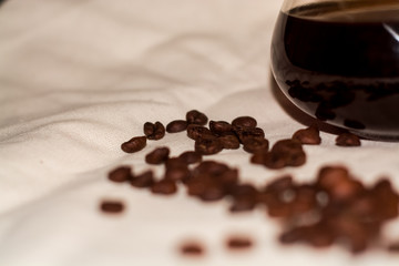 One-tone light background of coarse fabric. Arabica coffee beans are scattered. Caffeine drink.