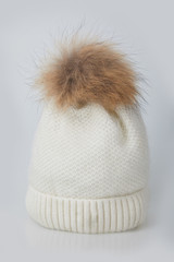 Beautiful luxury women's knitted hat with fur on a white background