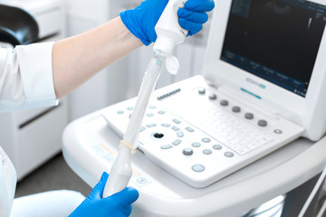 gynecologist doctor prepares an ultrasound machine for the diagnosis of the patient. Applies gel to a transvaginal ultrasound scanner. Women's Health Concept