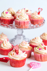 Several strawberry cupcakes with cream cheese frosting and sprinkles for Valentine's Day.