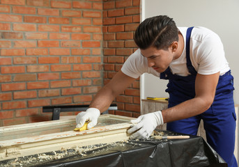 Man repairing old damaged window at table indoors