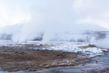 An erupting soaring geyser in the Valley of Geysers. Magnificent Iceland in the winter.