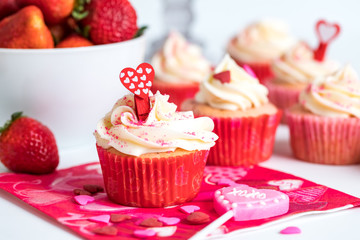 A close up of strawberry cupcakes with cream cheese frosting and sprinkles ready for eating for Valentine's Day.
