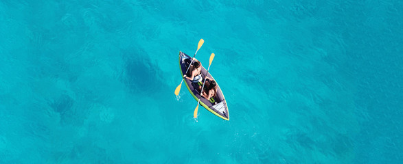 Aerial drone ultra wide photo of 2 unidentified fit women canoeing in tropical Caribbean exotic...