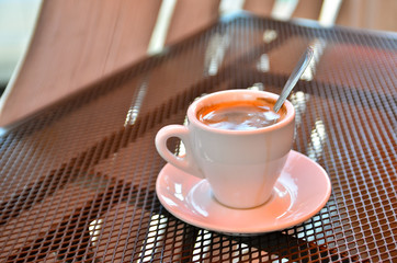A cup of coffee on a metal grated table in a cafe