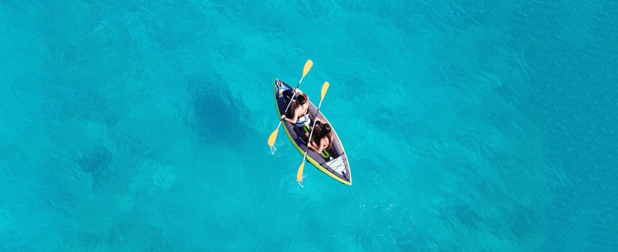 Aerial drone ultra wide photo of 2 unidentified fit women canoeing in tropical Caribbean exotic destination with turquoise sea