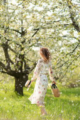 Fototapeta na wymiar A gorgeous girl walks in a flowering spring garden. The concept of unity of man with nature