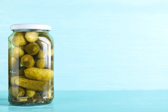 Glass jar of pickles on light blue wooden table. Space for text