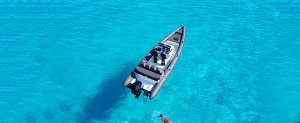 Aerial top view ultra wide luxury inflatable rib speed boat docked in exotic turquoise open ocean...