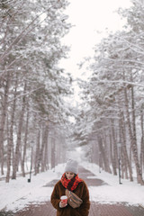 Woman drinking coffee in winter snow forest.