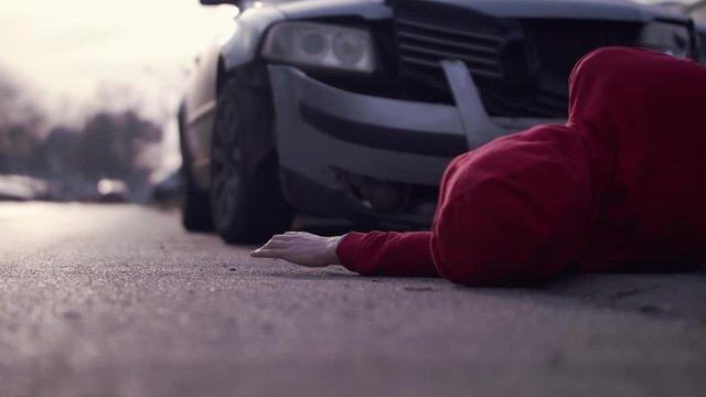 injured pedestrian in jumper lying on the street in a car accident. Struggling Injured at a car accident site. CloseUp, zoom out
