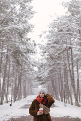 Woman drinking coffee in winter snow forest.