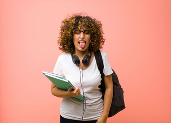 young pretty student woman with cheerful, carefree, rebellious attitude, joking and sticking tongue...