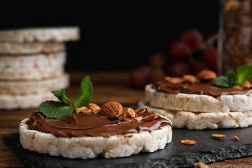 Fototapeta premium Puffed rice cakes with chocolate spread, nuts and mint on slate board, closeup