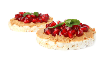 Puffed rice cakes with peanut butter, pomegranate seeds and mint isolated on white