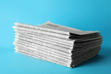 Stack of newspapers on light blue background. Journalist's work
