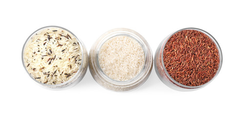 Brown and polished rice in jars isolated on white, top view