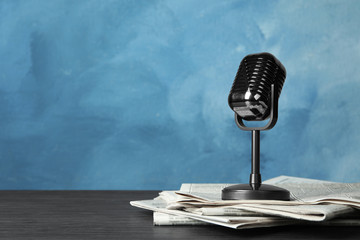Newspapers and vintage microphone on table, space for text. Journalist's work