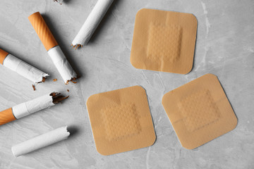 Nicotine patches and broken cigarettes on grey table, flat lay