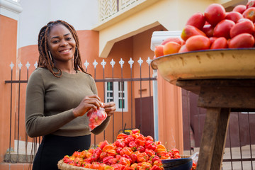young pretty african trader feeling excited as she is packaging her tomatoes.
