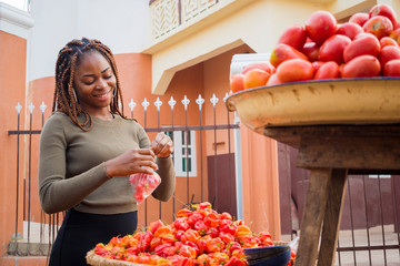 young pretty african trader feeling excited as she is packaging her tomatoes.
