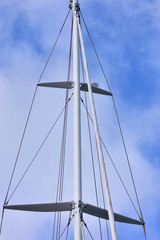 Top half of sail boat mast with spreaders and shrouds and furling headsail.