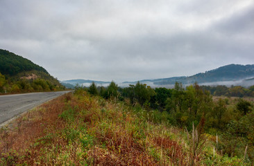 Autumn valley, road going into the foggy mountains