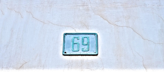 Number 69, sixty-nine, old weathered plate on an aged wall background.