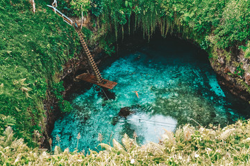 Natural water-filled sinkhole with giant ladder leading down onto diving plank