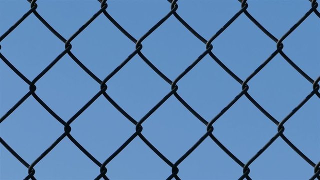 Camera sliding around the wired fence with blue sky close up