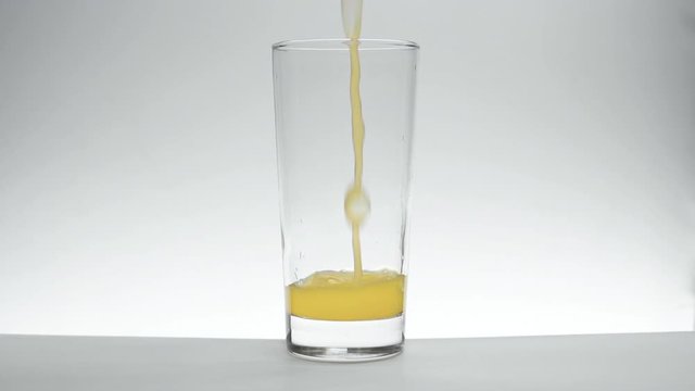 Orange Juice poured into a glass on a white background in slow motion