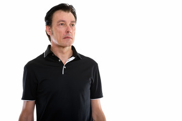 Studio shot of mature handsome man thinking while looking at distance