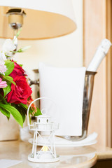 Lighthouse candle holder with champagne bottle and flower basket in the upscale hotel room. Being alone, getaway, staycation, digital detox, summer vacation concepts. Vertical