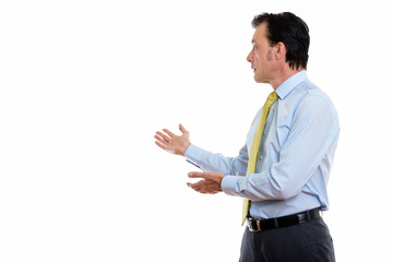 Studio shot of mature handsome businessman showing something at the back