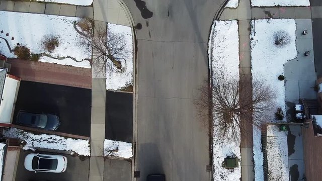 drone flies over a deserted neighborhood street during winter. snow on sidewalks