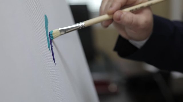 man paints on canvas with green paint