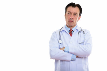 Studio shot of mature handsome man doctor thinking with arms crossed