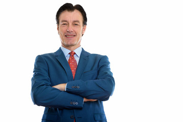 Studio shot of mature happy businessman smiling with arms crossed