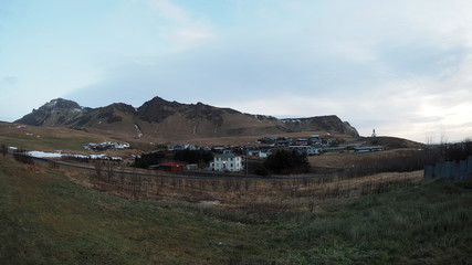 Vik town panoramic view, Iceland, houses sit under mountain range, and church at the top of a hill