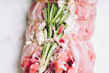 Raw pork loin with fruits, blue cheese and rosemary ready for baking. Selective focus. Shallow depth of field.