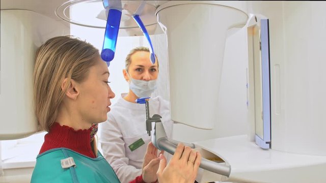 Doctor to take a image 3d scanner tomography of teeth and jaw in modern laboratory dental clinic. Female nurse shows the patient woman an x-ray machine 3d digital scanner. Computer dental diagnostics.